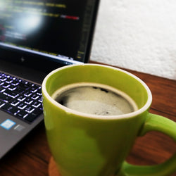 taza de ver de café sin nombre a lado de una computadora